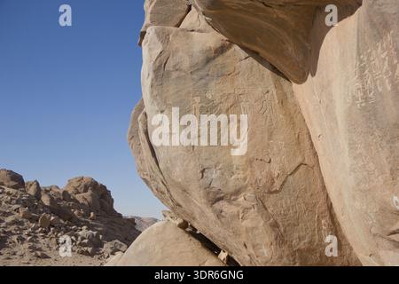 Grand rocher de granit avec des panneaux en relief égyptiens anciens et des inscriptions sur l'île de Sehel près d'Assouan, en Égypte, dans un paysage désertique Banque D'Images