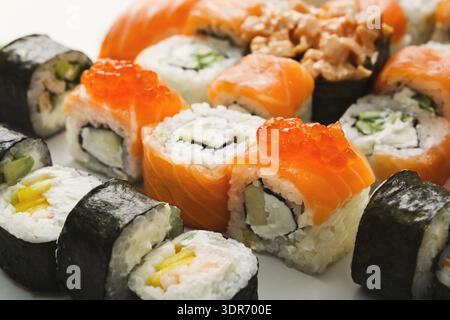 Différents types de Sushi avec des rouleaux de saumon, de crabe et de concombre sur une assiette blanche Banque D'Images