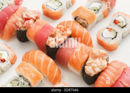 Différents types de Sushi disposés soigneusement sur une surface blanche avec différentes garnitures et garnitures Banque D'Images