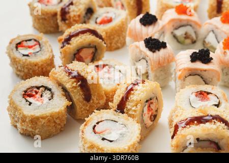 Sushi Rolls sur une assiette blanche avec différents fruits de mer et garnitures soigneusement disposés Banque D'Images