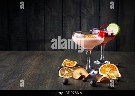 Cocktails colorés avec fruits séchés sur la table en bois dans le cadre du bar en soirée Banque D'Images