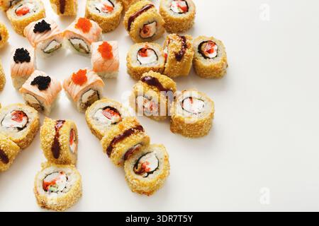 Différents types de sushi disposés soigneusement sur un fond blanc pour une présentation alimentaire Banque D'Images