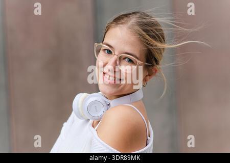 Jeune étudiante souriante portant des lunettes et des écouteurs Banque D'Images