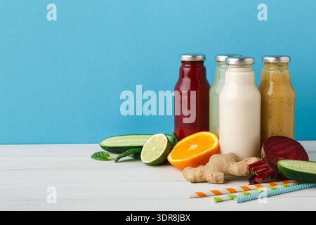 Variété de jus de fruits frais affichés sur une table avec des fruits et légumes dans un cadre lumineux Banque D'Images