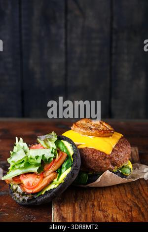 Hamburger gastronomique avec pain noir et garnitures servi sur une table en bois dans un cadre décontracté Banque D'Images