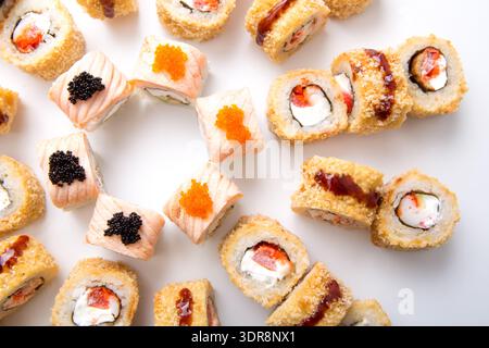 Rouleaux de sushi disposés sur une assiette blanche montrant différents types et styles lors d'un repas Banque D'Images