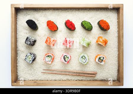 Différents types de Sushi disposés sur une surface blanche avec des baguettes à proximité pour manger Banque D'Images