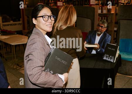 Jeune femme asiatique tenant le livre tout en assistant à l'événement de présentation d'auteur Banque D'Images