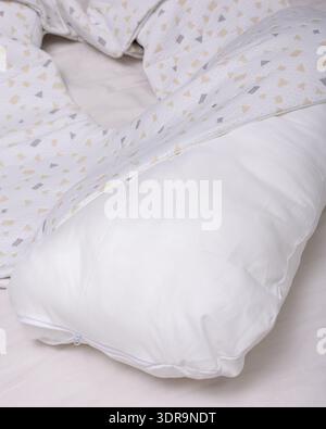Oreiller de maternité blanc doux en forme de U avec housse amovible à motifs géométriques, idéal pour les femmes enceintes, l'allaitement et un soutien confortable du sommeil pendant Banque D'Images