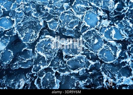 Gros plan de morceaux de glace fissurés à la surface d'une rivière, créant une texture naturelle époustouflante. Fond de gel d'hiver parfait avec des motifs complexes an Banque D'Images