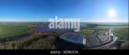 Vue aérienne de panneaux solaires brillants sous le soleil brillant, moulins à vent debout haut au milieu des champs verts, Chelverston, Wellingborough, Royaume-Uni Banque D'Images