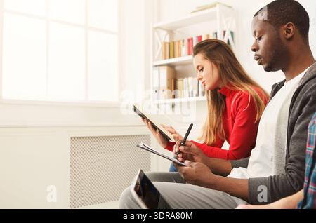 Les gens s'engagent dans la lecture et l'écriture pendant une activité de groupe dans une salle lumineuse Banque D'Images
