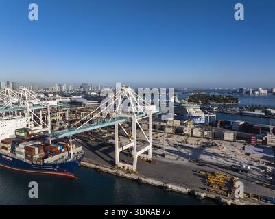 Vue aérienne des cargos amarrés à Port Miami, avec la ligne d'horizon de la ville s'estompant à l'horizon sous un ciel bleu clair, Miami, Floride, États-Unis. Banque D'Images