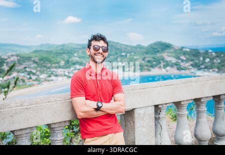 Portrait de touriste souriant dans un point de vue d'une baie. Bel homme de tourisme regardant la baie de San Juan del sur Banque D'Images