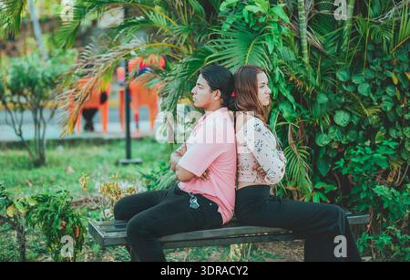 Un jeune couple bouleversé assis dos à dos sur un banc. Couple malheureux se disputant sur un banc public. Concept de problèmes de couple et cri Banque D'Images