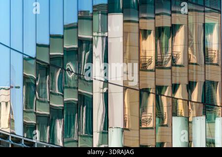 Les bâtiments en face se reflètent dans la façade vitrée d'un immeuble de bureaux moderne Banque D'Images
