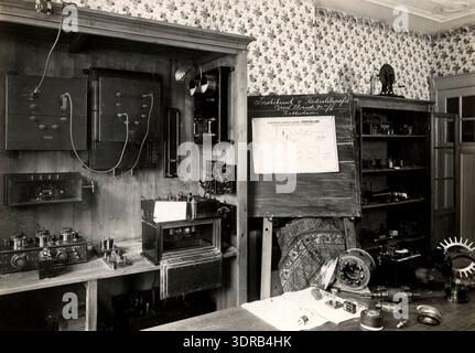 Cette photographie de 1923 de Richard Strauss montre une salle à l'intérieur de l'Institut de radiotélégraphie de Rotterdam, aux pays-Bas, contenant divers appareils électriques et radio. L'image documente l'équipement télégraphique du début du XXe siècle, les paramètres de salle de classe, la formation technique, la pratique des étudiants, les appareils électriques, technologie radio néerlandaise, infrastructure éducative et enseignement technologique européen en 1923. Banque D'Images