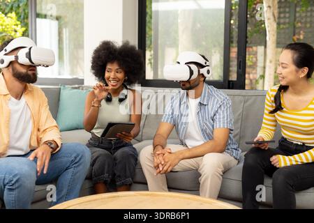 En utilisant des casques VR, de jeunes amis divers appréciant l'expérience de réalité virtuelle ensemble Banque D'Images