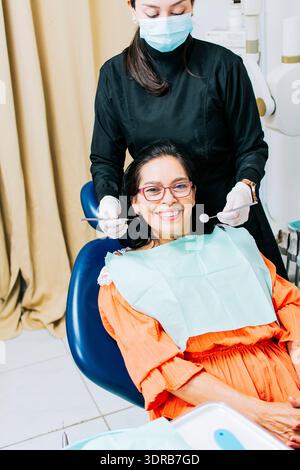 Dentiste examinant la bouche à la patiente souriante, dentiste femme faisant le canal radiculaire à la patiente féminine, dentiste femme avec le patient couché Banque D'Images