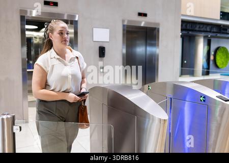 Entrée dans l'immeuble de bureaux, femme utilisant la carte d'accès au tourniquet de sécurité Banque D'Images