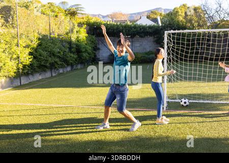 Jouer au football, garçon célébrant le but avec des amis sur le terrain extérieur, copier l'espace Banque D'Images