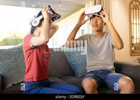 En utilisant des casques VR, deux adolescents assis sur le canapé appréciant la réalité virtuelle Banque D'Images