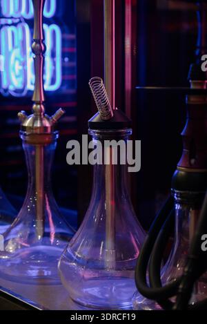 Hookahs en verre sur un comptoir de bar dans une discothèque avec éclairage au néon.hookahs modernes en verre et en métal dans un salon de hookah avec néon bleu Banque D'Images