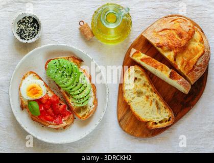 Sandwichs de pain de blé avec fromage à la crème (ricotta), avocat, œufs, tomate, basilic, sésame noir et blanc. Délicieux Brea sain Banque D'Images