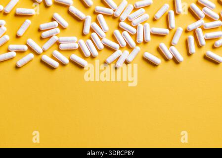Capsules médicales blanches sur fond jaune. Banque D'Images