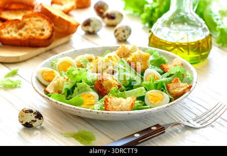 Délicieuse salade gourmande de laitue, œufs de caille, croûtons à l'ail et vinaigrette à l'huile d'olive au citron ju Banque D'Images
