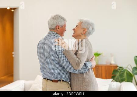 Continuez à bouger. Couple senior romantique dansant sur la musique ensemble à la maison. Heureuse famille souriante homme retraité femme mari wif Banque D'Images
