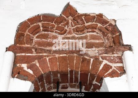 Arc historique décoratif en briques rouges présentant des motifs détaillés de maçonnerie et de mortier dans les murs en plâtre blanc du Kremlin de Rostov Veliky Banque D'Images
