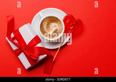 Une délicieuse combinaison d'une tasse de café vapeur et d'une sucette en forme de cœur Banque D'Images
