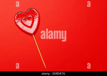 Sucette en forme de coeur sur un fond rouge vif Banque D'Images
