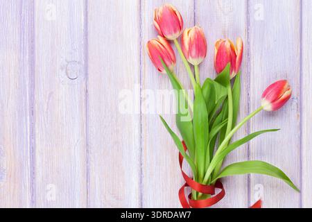 Tulipes rouges sur table en bois violet Banque D'Images