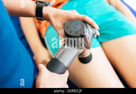 Physiothérapeute utilisant un pistolet de massage pour soulager les douleurs musculaires, la percussion ou la thérapie vibratoire. Physiothérapeute utilisant le pistolet de massage Banque D'Images