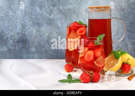 Le thé glacé à la fraise ou le smoothie au citron à la menthe est une recette rafraîchissante de boisson estivale. Verre avec limonade de fruits de baies sur un concr léger Banque D'Images