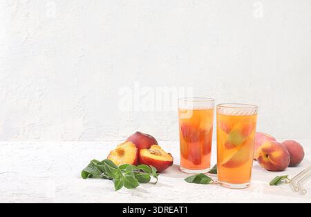 Thé de pêche glacé ou cocktail à la menthe et au lobdom, recette pour rafraîchir la boisson estivale.deux verres avec limonade de fruits de pêche sur Ligh Banque D'Images