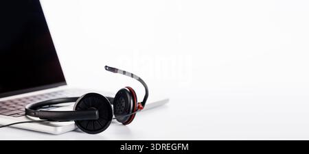 Un casque élégant reposant sur un ordinateur portable, sur un fond blanc brillant Banque D'Images