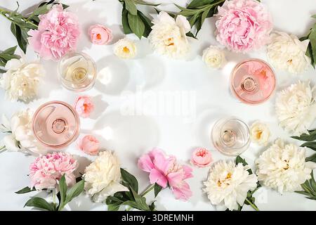 Composition florale avec différentes variétés de vin rosé, cocktail alcoolisé d'été pour une fête et fleurs de pivoine sur un bac léger Banque D'Images