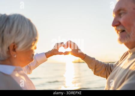 Amour coeur forme la paix. Couple aîné plus âgé faisant forme de coeur avec leurs mains. Adulte femme adulte vieux mari montrant le coeur sig Banque D'Images