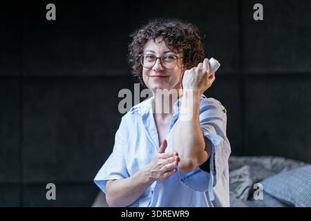 Confiant mature âge moyen femelle blanche appliquant la lotion sur le bras Banque D'Images