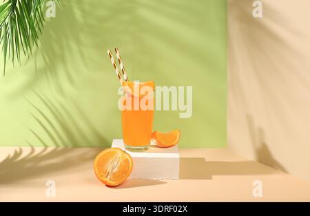 Nature morte moderne avec des agrumes, du jus d'orange et des oranges sur un fond pastel avec de longues ombres dures, un régime détox minimal Banque D'Images