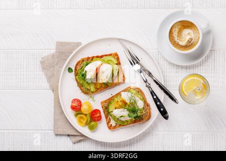 Délicieux toasts à l'avocat garni d'œufs pochés parfaitement cuits Banque D'Images