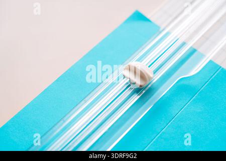 Vue inclinée du coupe-papier et de la feuille de papier bleue, outils de scrapbooking DIY sur le bureau pastel Banque D'Images