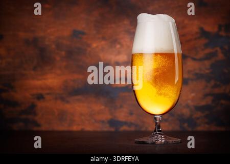 Un grand verre de bière avec une teinte dorée et la tête mousseuse Banque D'Images