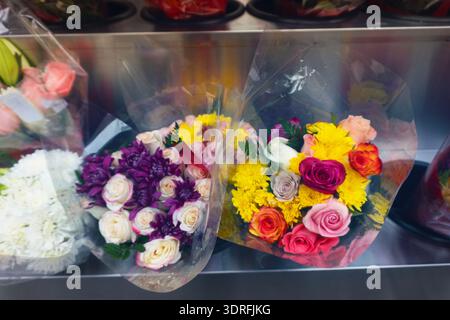 Superbe gros plan de roses rouges et jaunes fraîches disposées avec des perles dans un vase noir élégant, parfait pour les thèmes romantiques, de luxe ou de célébration. Banque D'Images