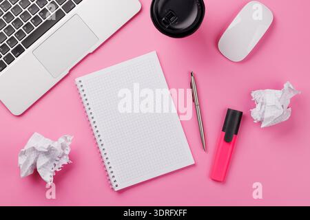 Vue de dessus d'un bureau rose avec fournitures de bureau, tasse à café et bloc-notes vierge Banque D'Images