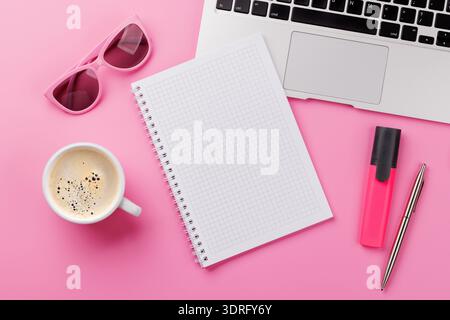 Vue de dessus d'un bureau rose avec fournitures de bureau, tasse à café et bloc-notes vierge Banque D'Images