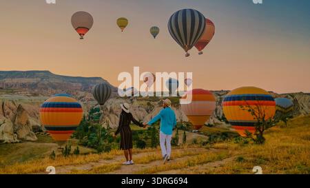 Couple apprécie la vue magique du lever du soleil des montgolfières en Cappadoce Turquie Banque D'Images
